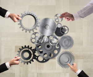 Teamwork of businesspeople work together and combine pieces of gears to a mechanical system