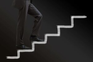 Businessman climbing stairs against a black background, symbolizing professional progress in the USA